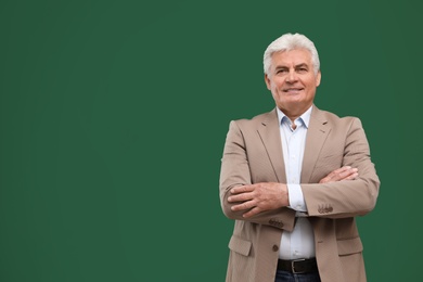 Portrait of senior teacher at green chalkboard, space for text