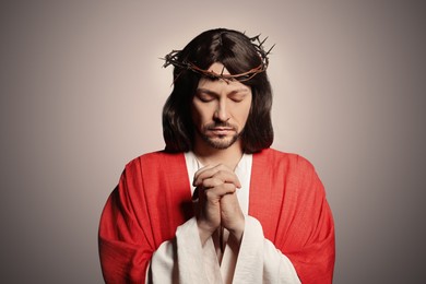 Photo of Jesus Christ with crown of thorns praying on beige background
