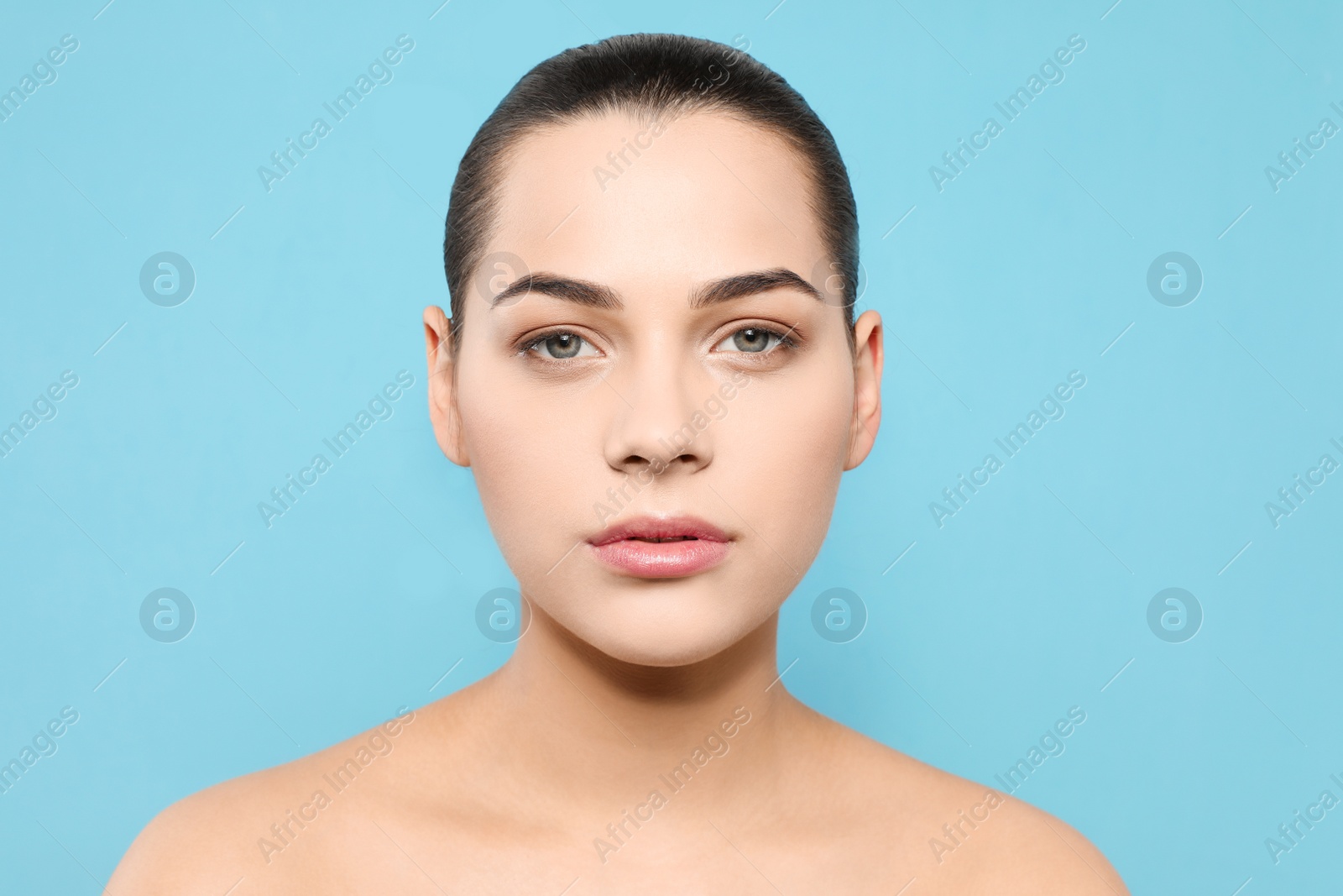Photo of Portrait of young woman with beautiful face and natural makeup on color background