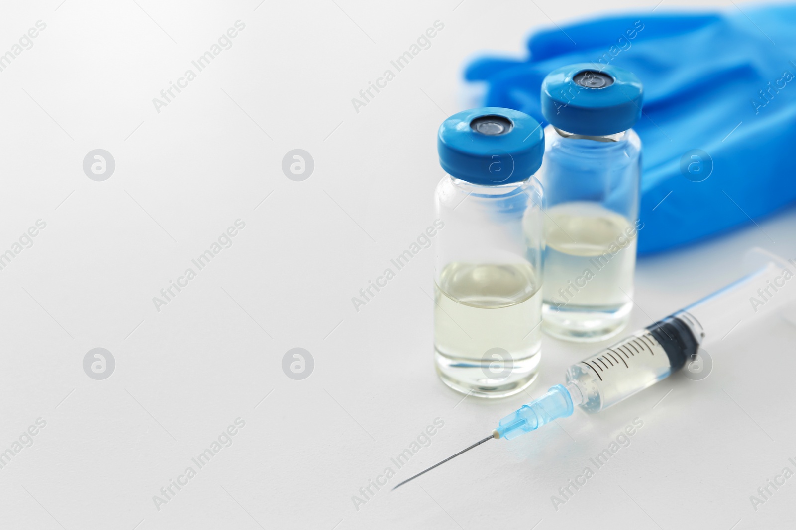 Photo of Vials and syringe with medicine on light background. Vaccination concept