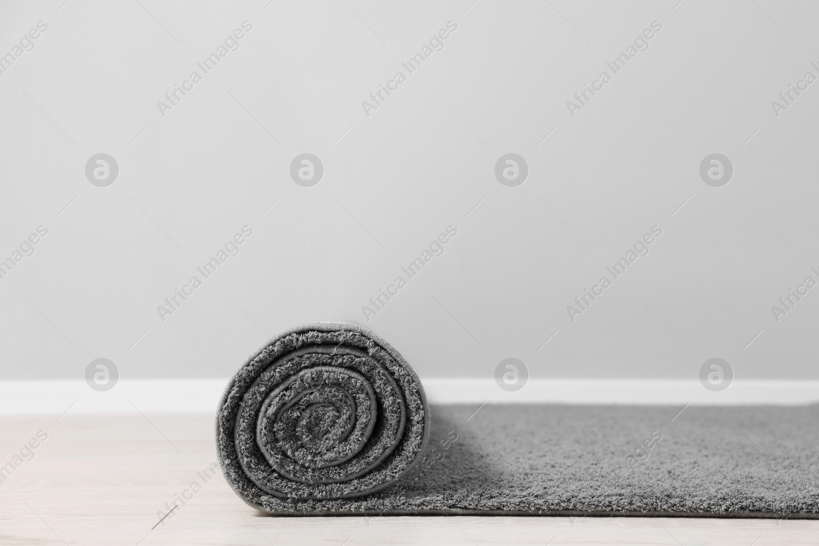 Photo of Rolled grey carpet on floor in room. Space for text