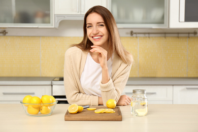 Photo of Young woman making lemon water in kitchen