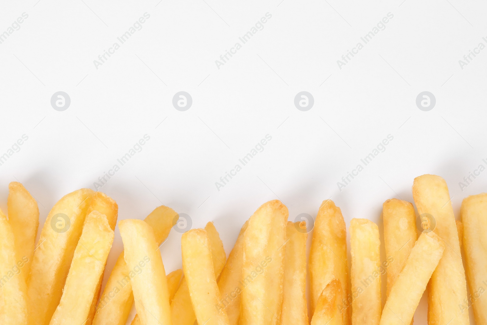 Photo of Delicious french fries on white background, flat lay. Space for text