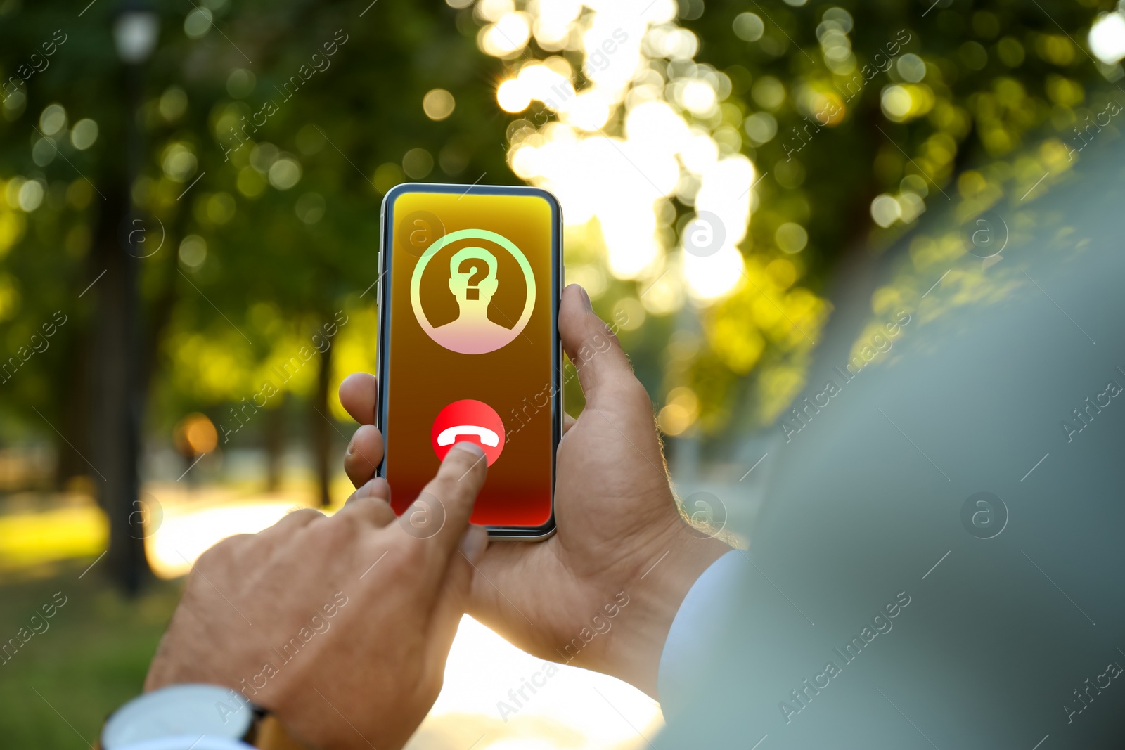 Image of Man declining incoming call from unknown caller in park, closeup. Be careful - fraud