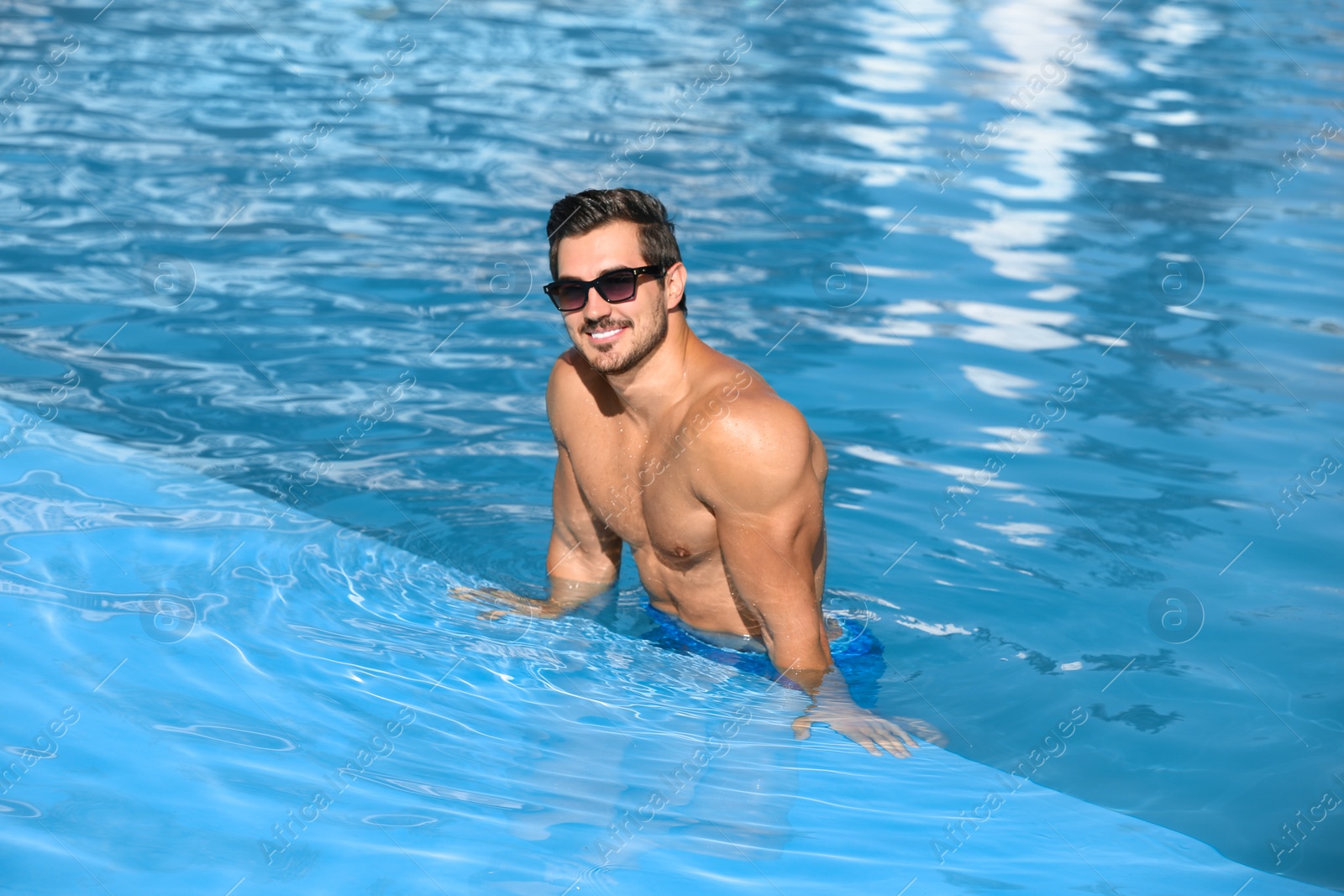 Photo of Handsome young man in swimming pool on sunny day