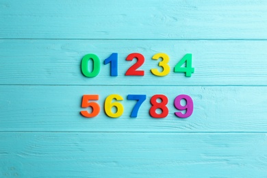 Photo of Colorful magnetic numbers on light blue wooden background, flat lay