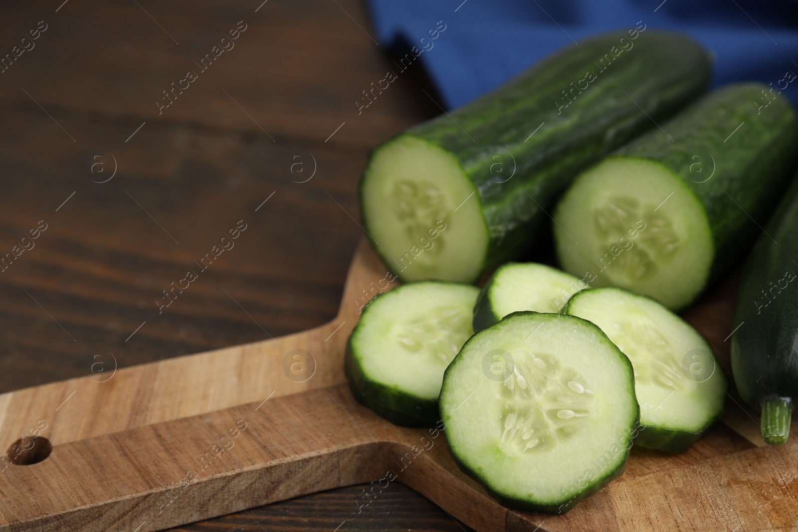 Photo of Fresh whole and cut cucumbers on wooden table, closeup