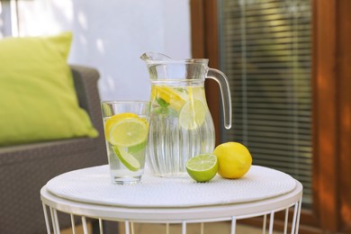 Water with lemons and limes on white table outdoors