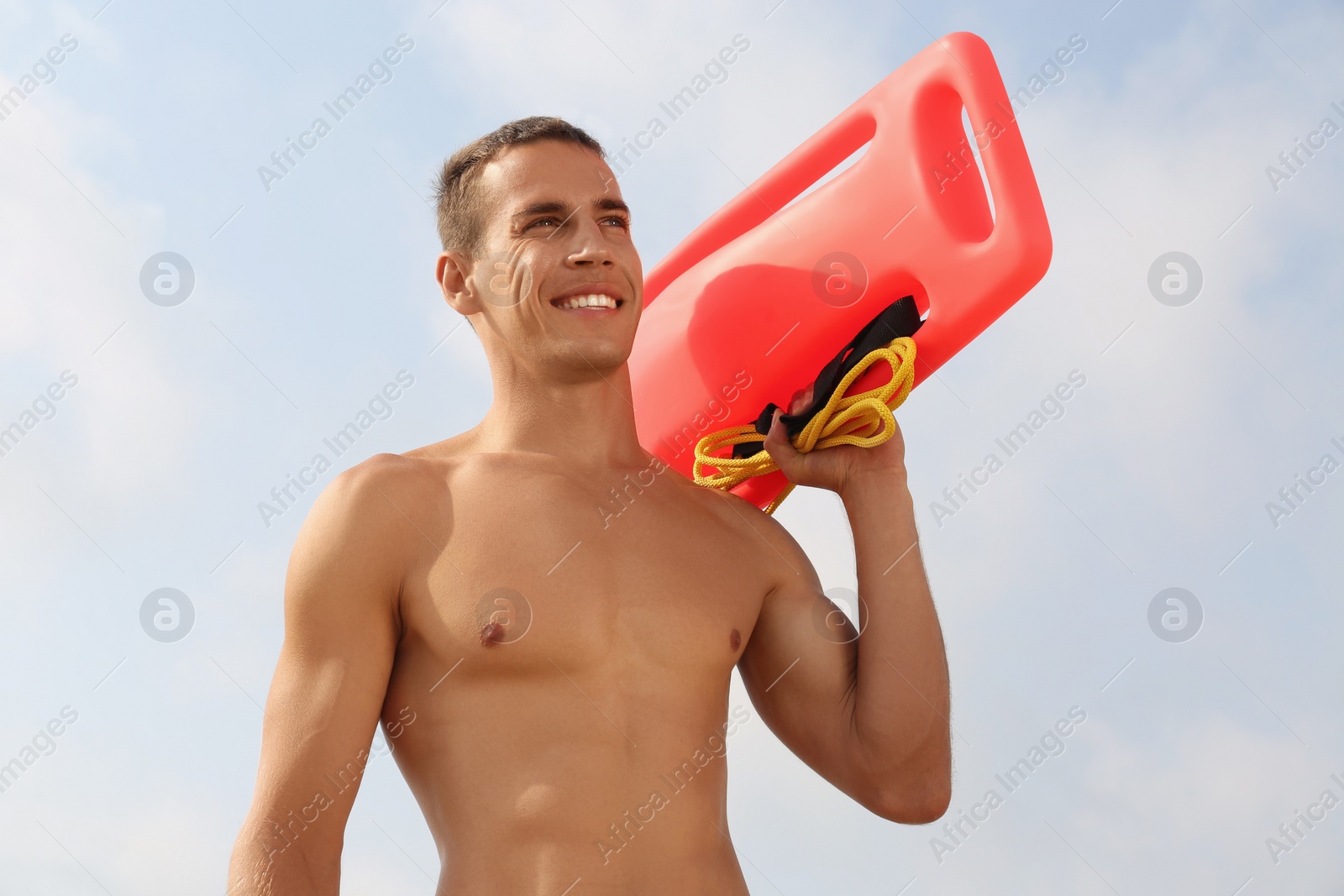 Photo of Handsome lifeguard with life buoy against blue sky