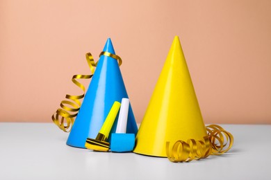 Photo of Colorful party hats, streamers and blowers on white table. Birthday celebration