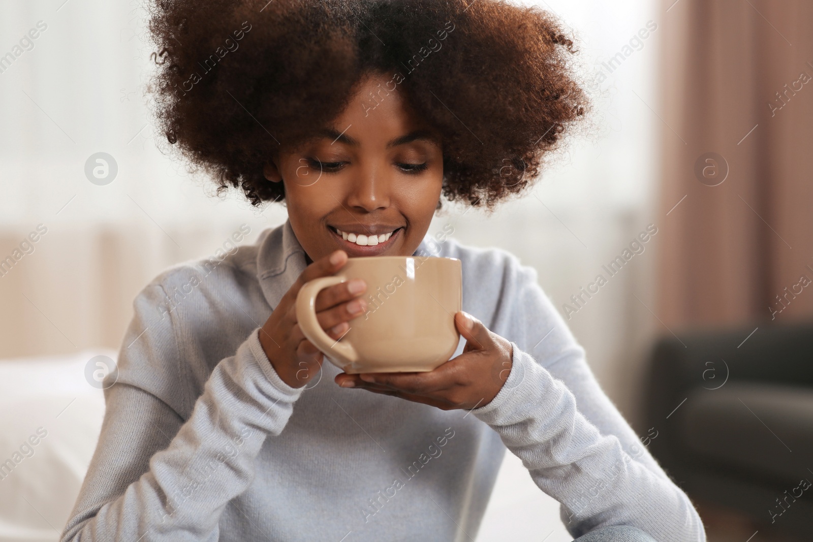 Photo of Smiling African American woman with cup of drink at home