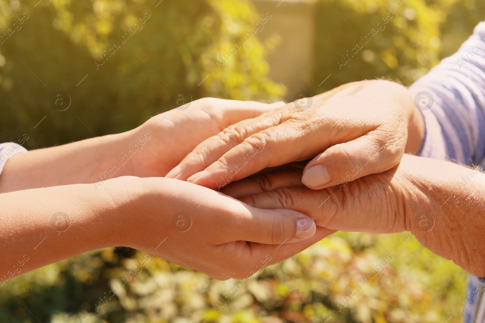 Photo of Helping hands on blurred background, closeup. Elderly care concept