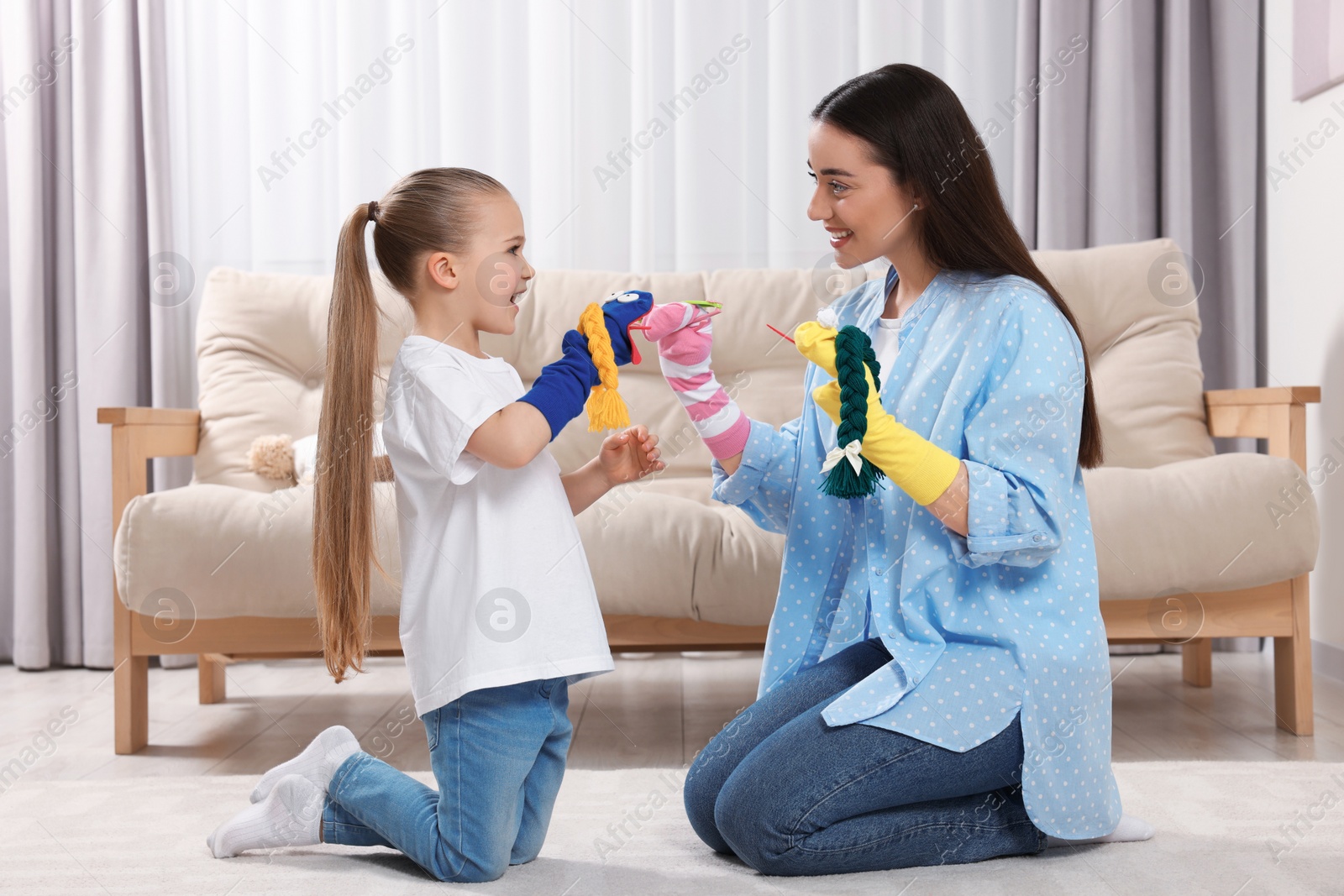 Photo of Happy mother and daughter playing with funny sock puppets together at home