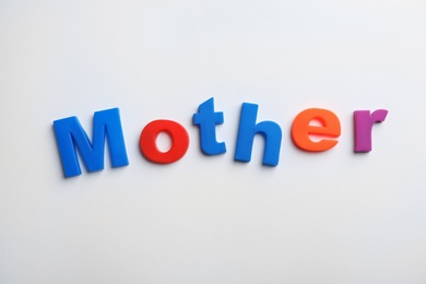 Word MOTHER of magnetic letters on white background, top view