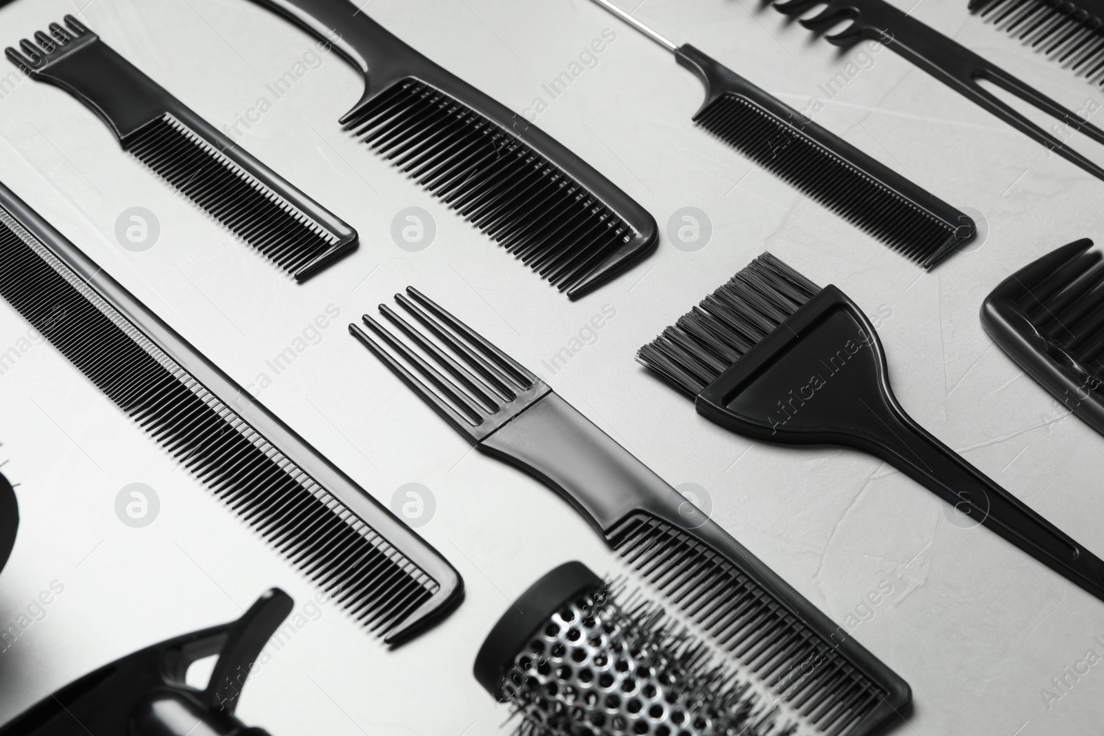 Photo of Different combs on light grey stone background, closeup