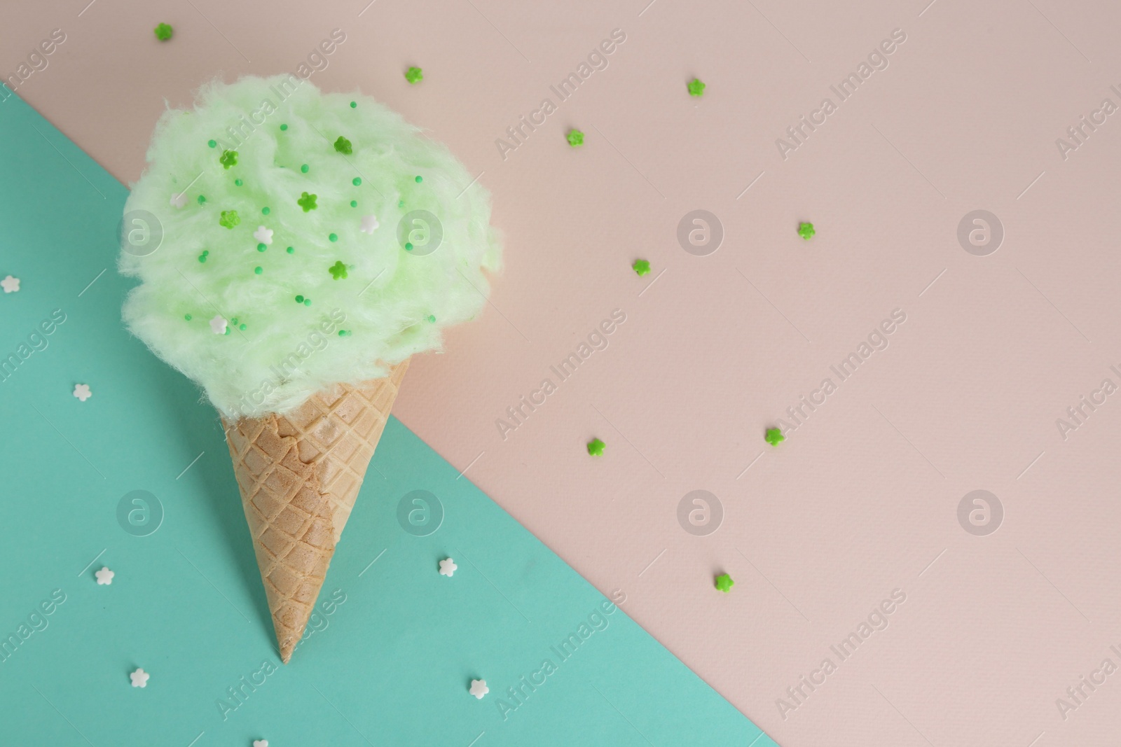 Photo of Sweet cotton candy in waffle cone on beige background, top view. Space for text