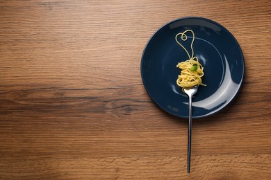 Photo of Heart made with spaghetti and fork on wooden table, top view. Space for text