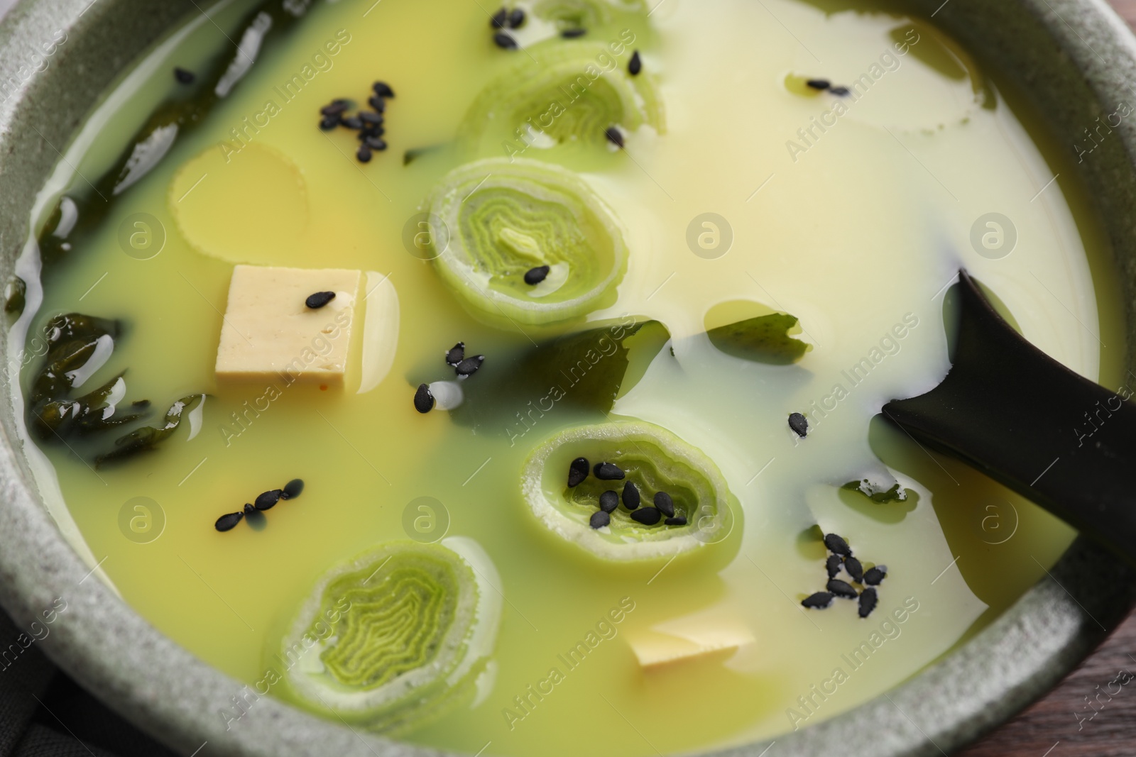 Photo of Bowl of delicious miso soup with tofu and spoon, closeup