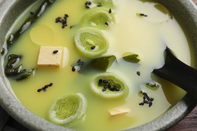 Photo of Bowl of delicious miso soup with tofu and spoon, closeup