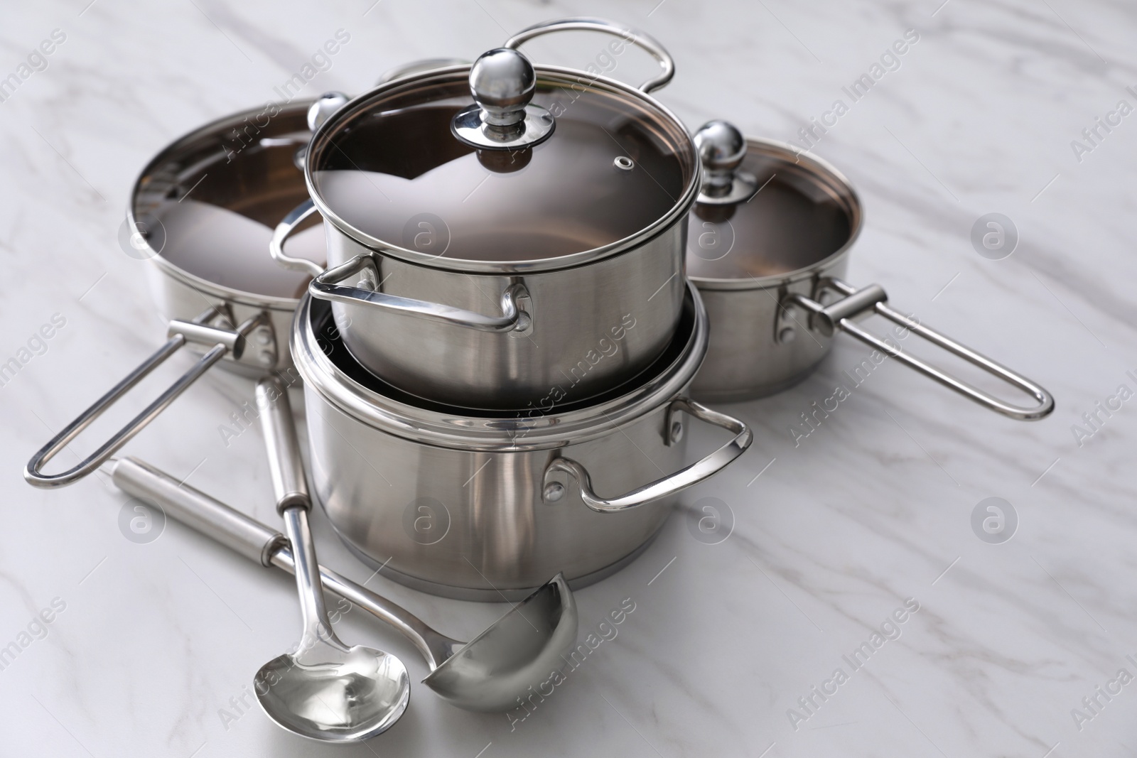 Photo of Set of new clean cookware and kitchen utensils on white marble table