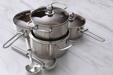 Photo of Set of new clean cookware and kitchen utensils on white marble table