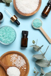 Aromatherapy products. Bottles of essential oil, sea salt and eucalyptus leaves on light blue background, flat lay