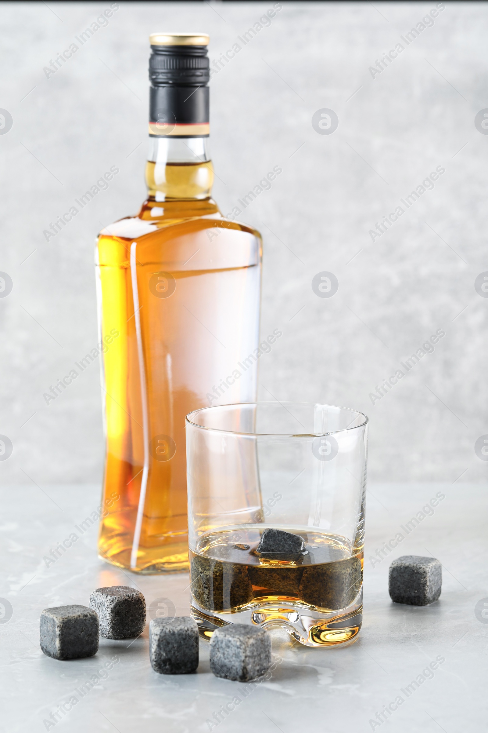 Photo of Whiskey stones and drink on light marble table, closeup