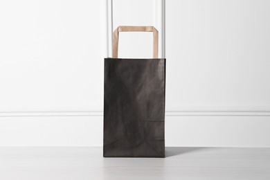 Black paper bag on white wooden table