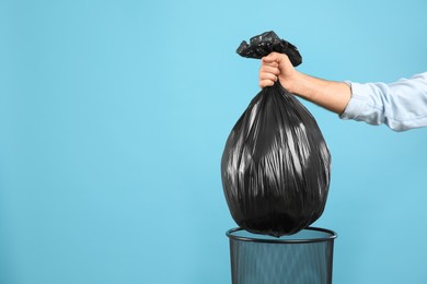 Photo of Woman taking garbage bag out of bin on light blue background, closeup. Space for text