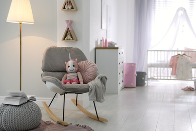 Photo of Cozy baby room interior with comfortable rocking chair