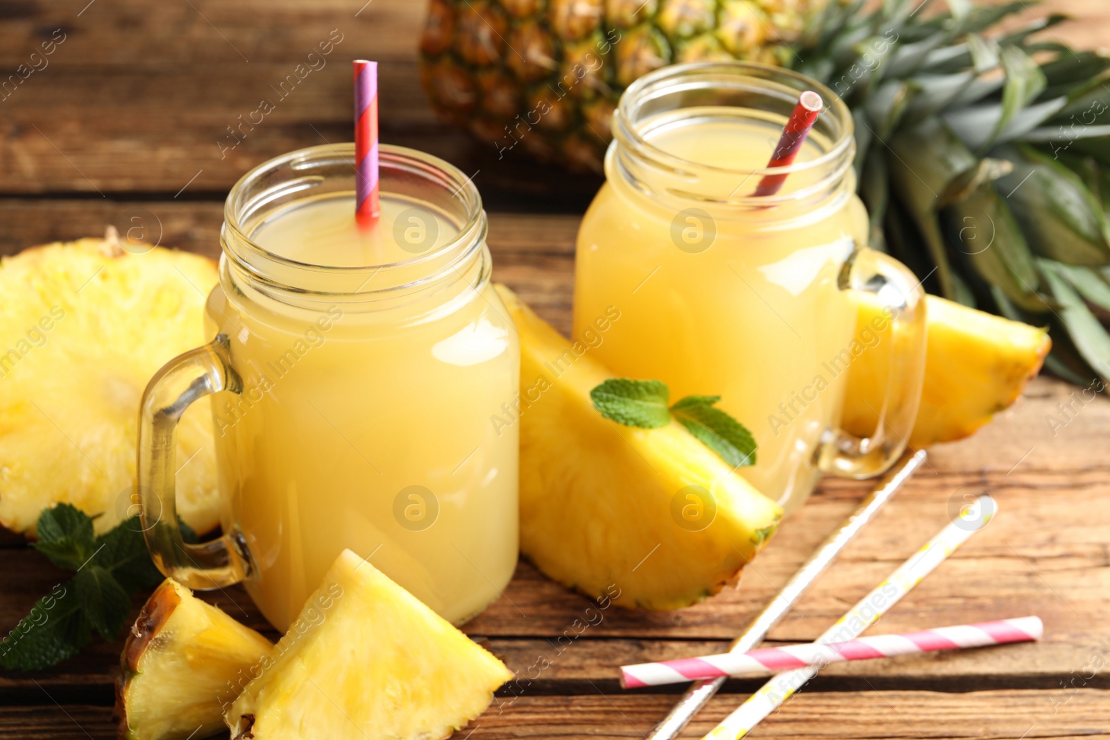 Photo of Delicious pineapple juice and fresh fruit on wooden table