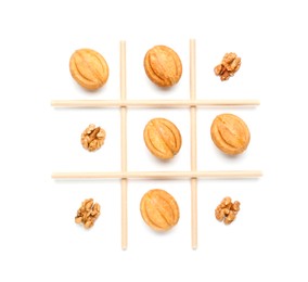 Photo of Tic tac toe game made with walnuts and cookies isolated on white, top view