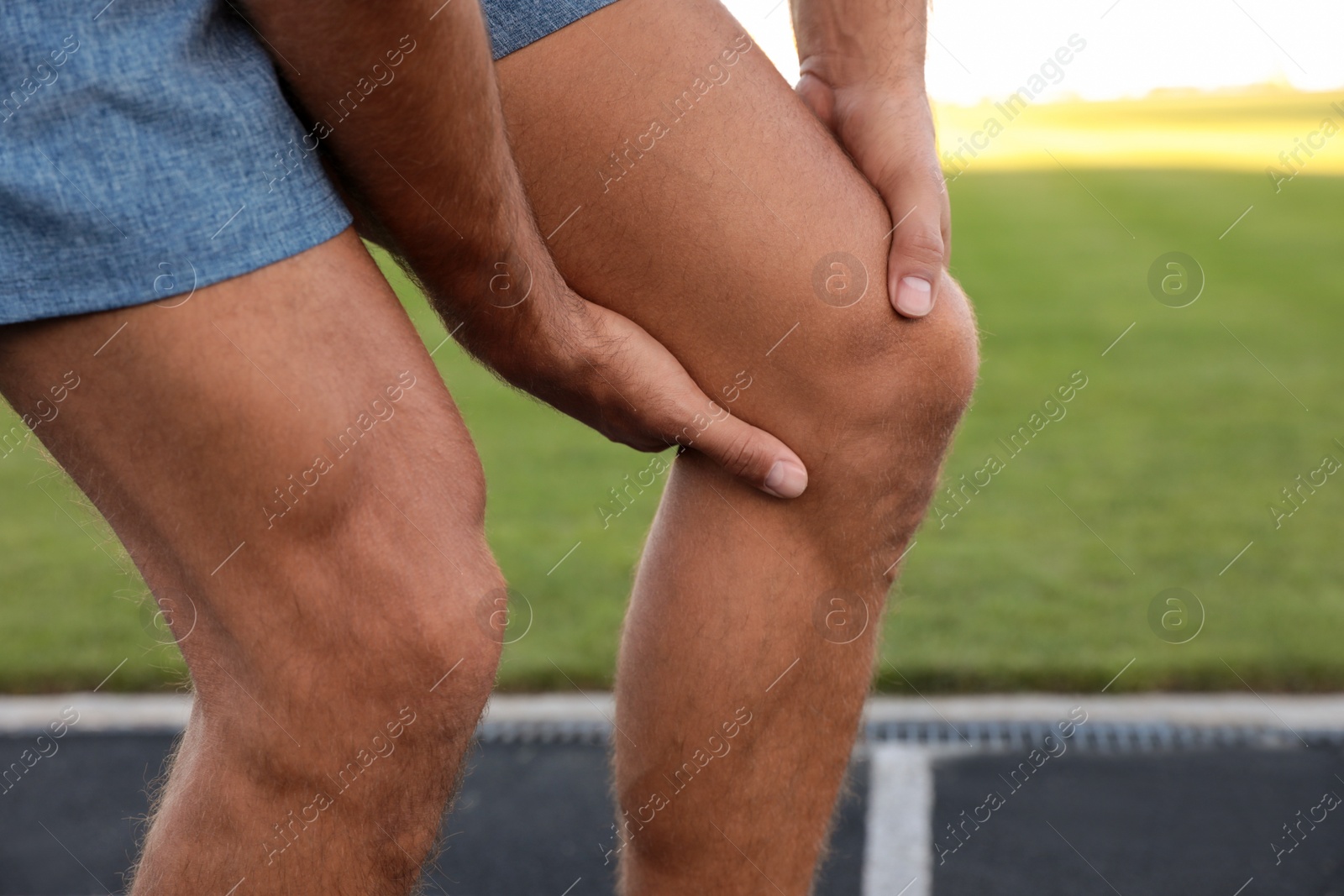 Photo of Man in sportswear having knee problems at stadium, closeup