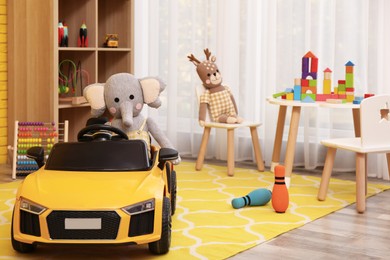 Child's electric car with toy elephant in playroom