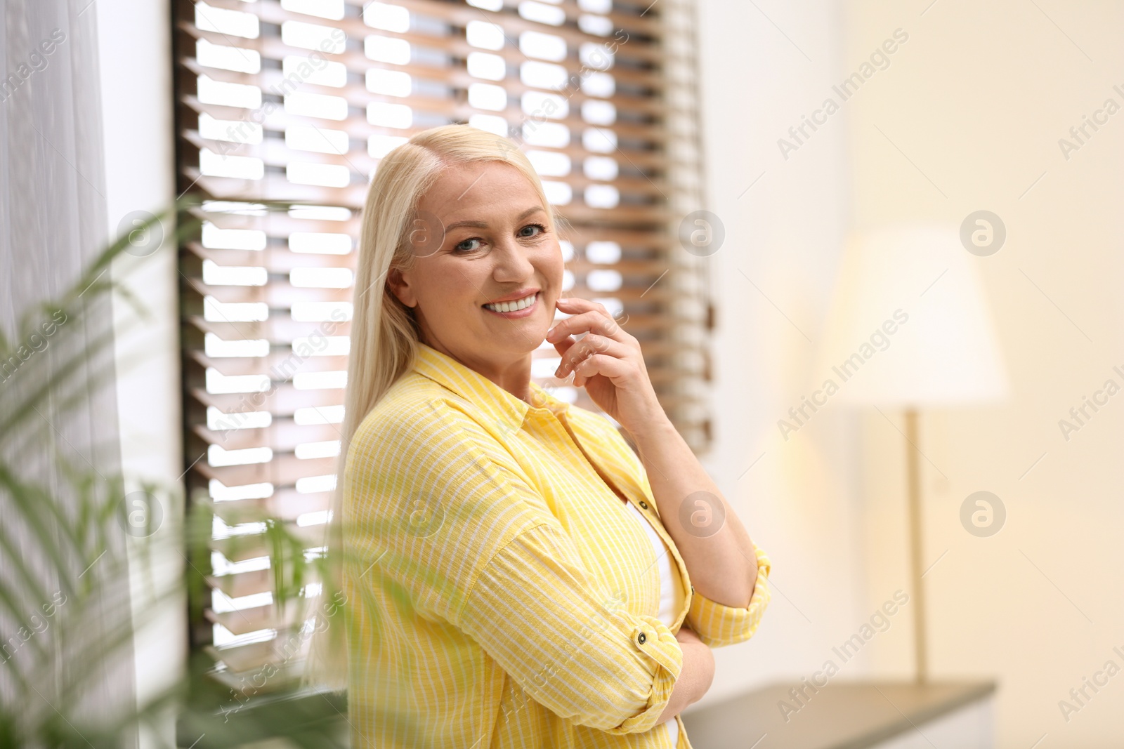 Photo of Portrait of happy mature woman near window indoors