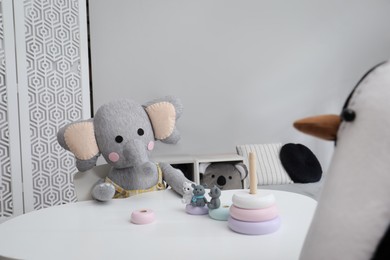 Photo of Cute toys at white table in child's room. Interior design