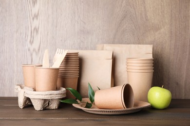 Set of disposable eco friendly dishware and apple on wooden table