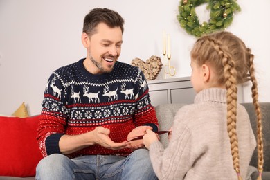 Photo of Happy man receiving greeting card from his daughter at home