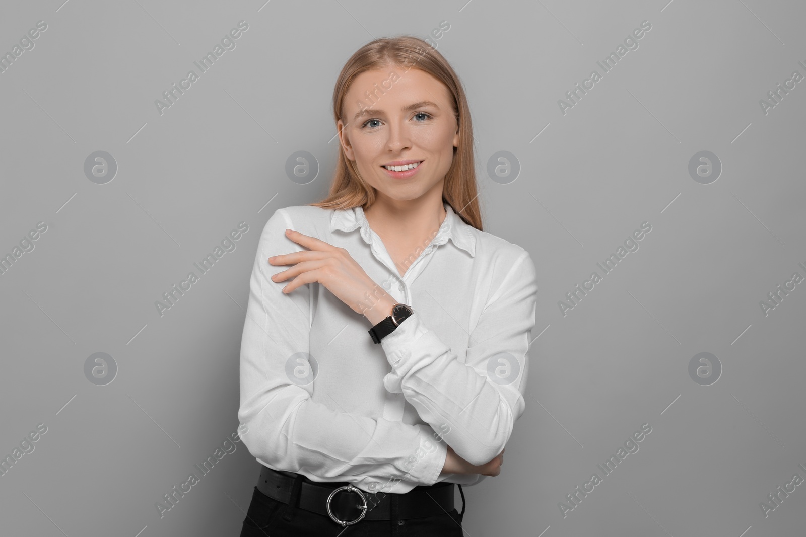 Photo of Portrait of beautiful young woman in white shirt on grey background