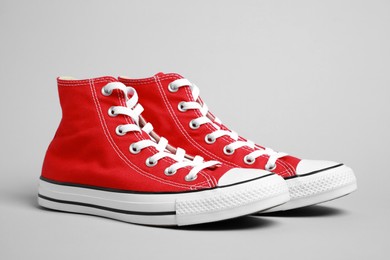 Photo of Pair of new stylish red sneakers on light grey background