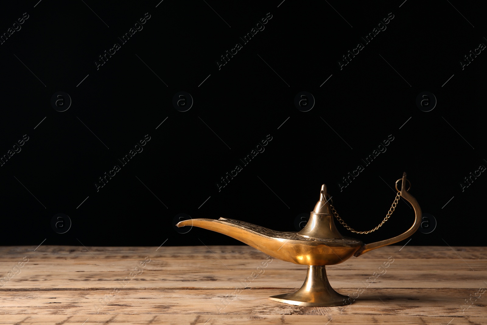 Photo of Aladdin lamp of wishes on wooden table against black background