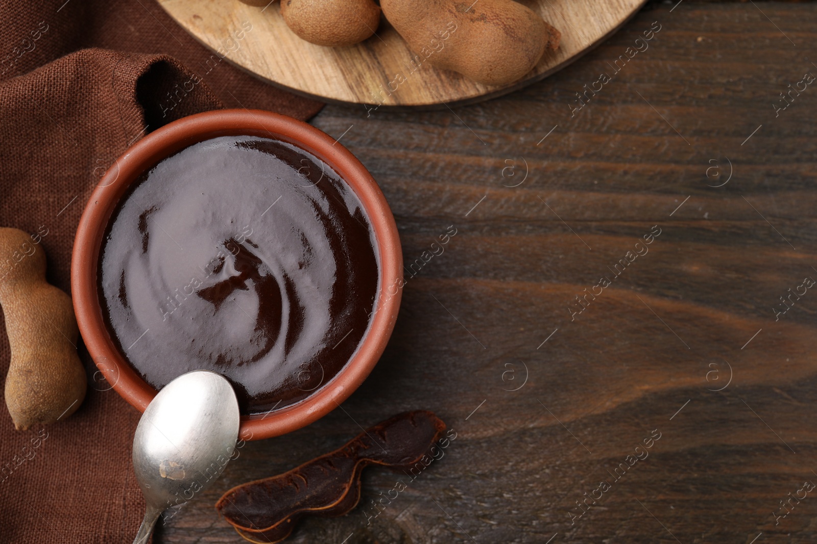 Bowl of tamarind sauce, spoon and fresh pods on wooden table, flat lay. Space for text Photo of Bowl of tamarind sauce, spoon and fresh pods on wooden table, flat lay. Space for text
