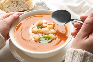 Woman eating sweet potato soup at table, closeup