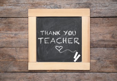 Image of Small blackboard with pieces of chalk and phrase Thank you, teacher on wooden table, top view