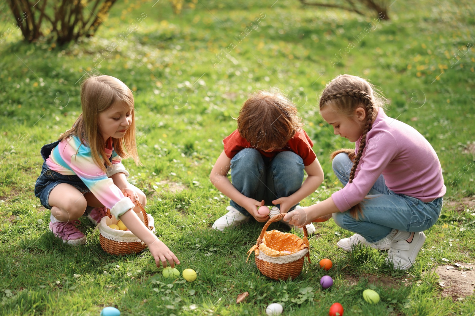 Photo of Easter celebration. Cute little children hunting eggs outdoors