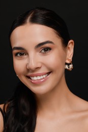 Photo of Young woman with elegant pearl earrings on black background