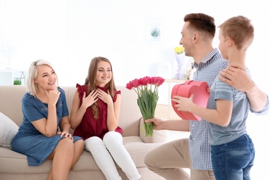 Photo of Man and little boy congratulating women at home