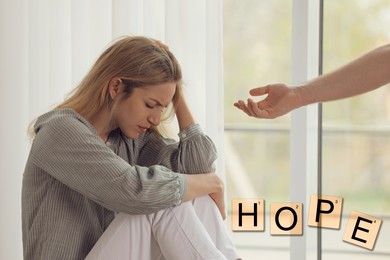 Concept of hope. Man offering hand to upset woman indoors
