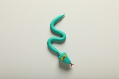 Photo of Turquoise plasticine snake isolated on white, top view
