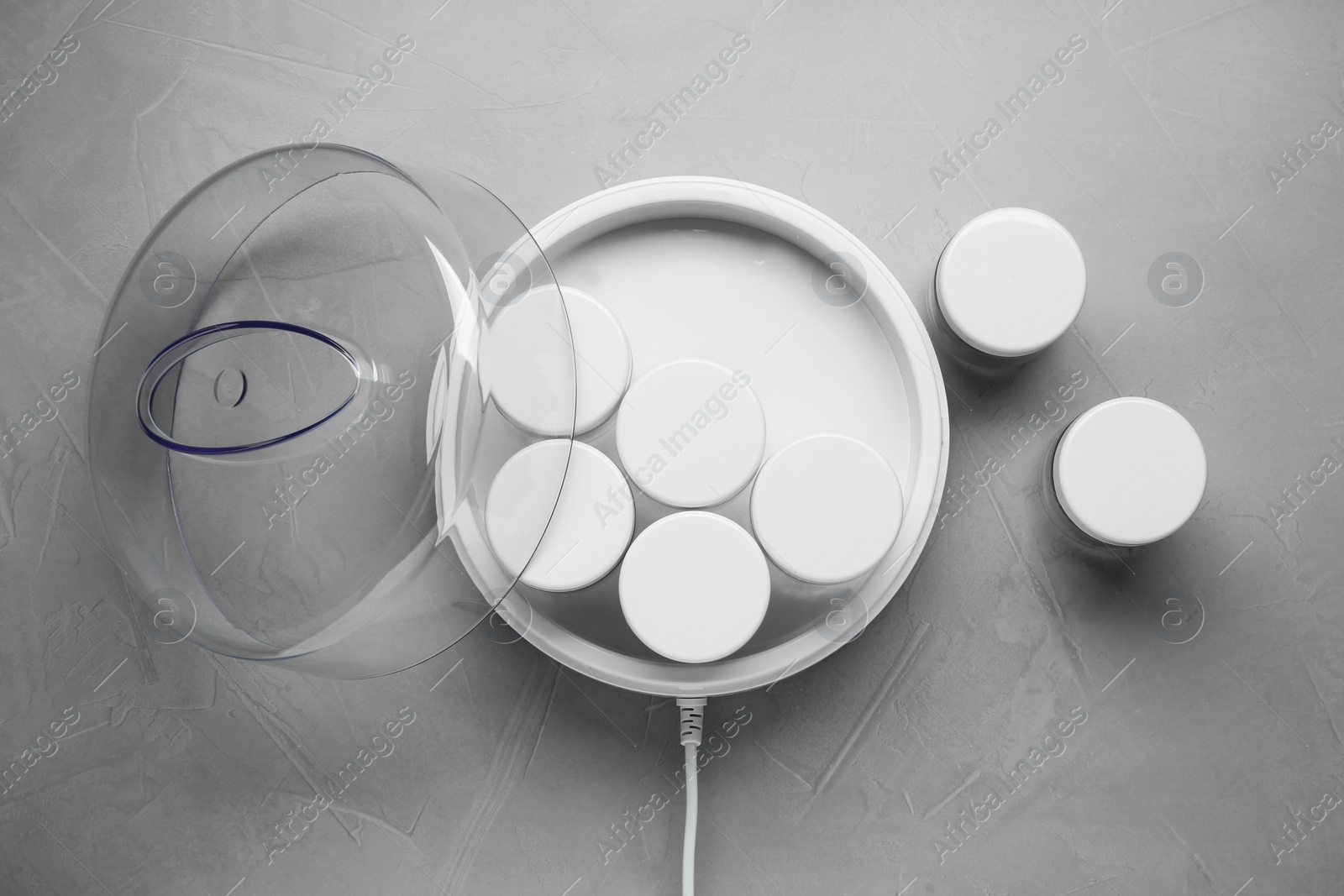 Photo of Modern yogurt maker with jars on light grey table, flat lay